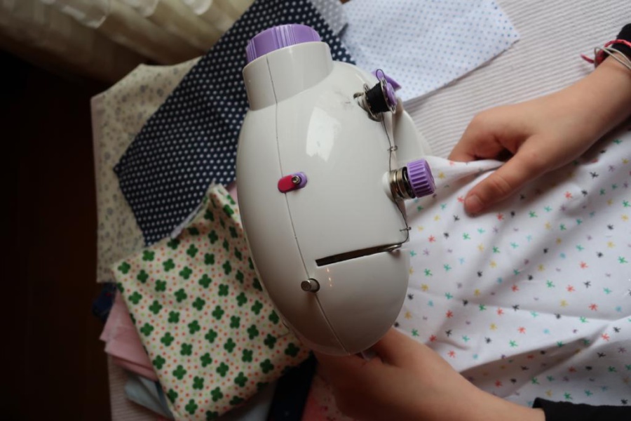 Candela practica la costura en su casa con su pequeña máquina de coser